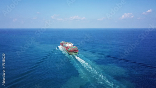 Huge large mega container ship sails on open water fully loaded with containers and cargo - aerial view
