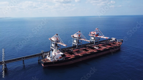 Large bulk carrier ship docking - Unloading coal ship by cranes on the power station dock photo