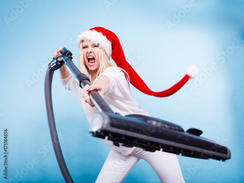 Angry girl in santa helper hat with vacuum cleaner photo