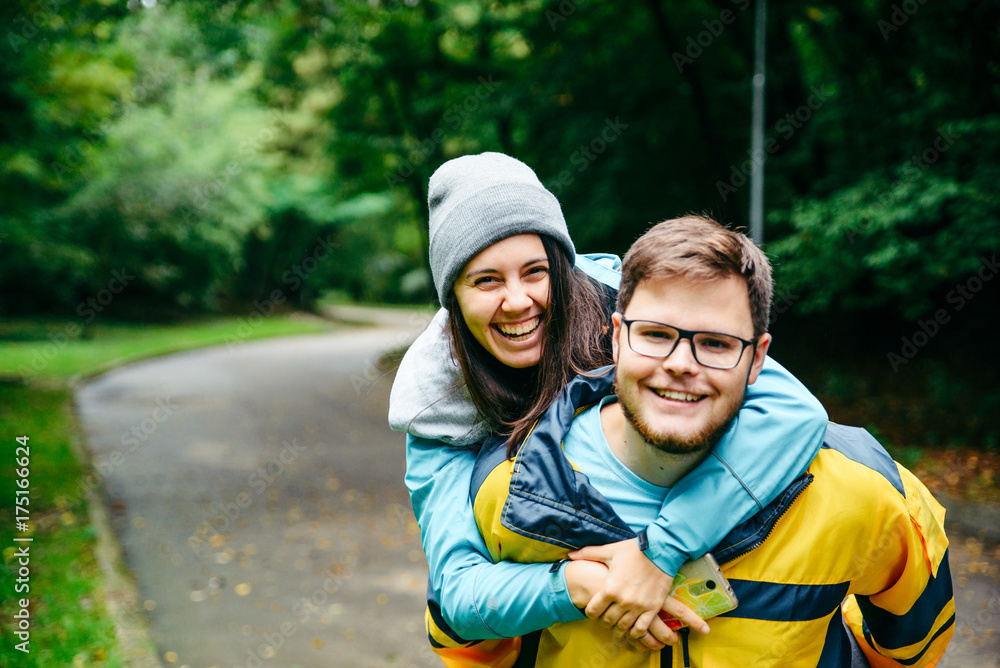 laughing couple in sport wear, woman jump on man shoulders laughing couple in sport wear, woman jump on man shoulders