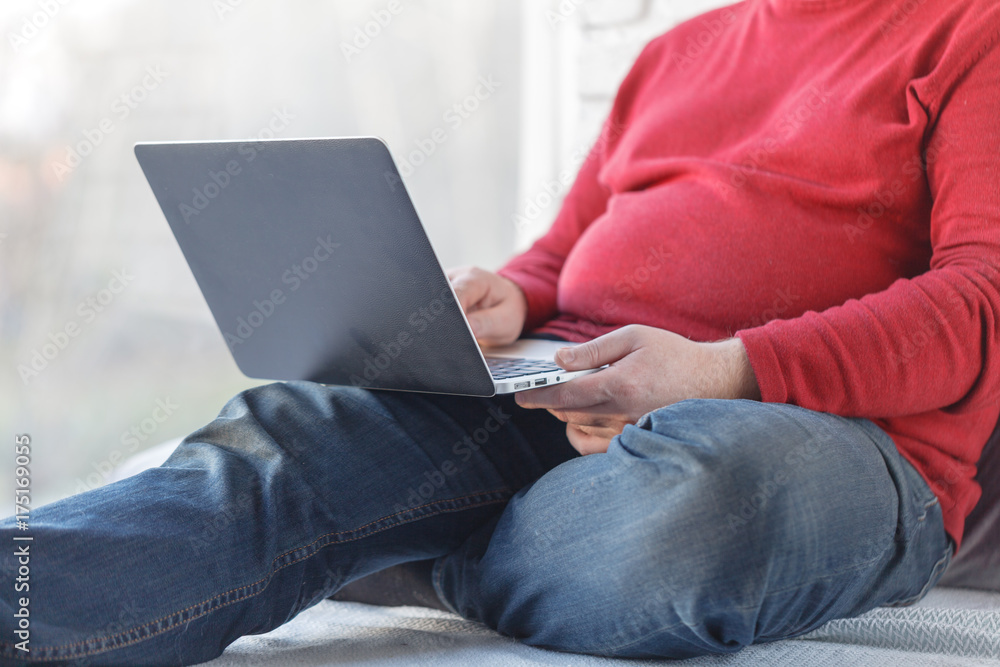 Casual man sitting and working with laptop on wooden floor Casual man sitting and working with laptop on wooden floor