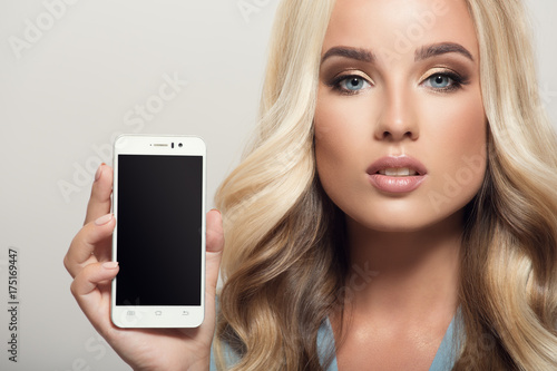 Beautiful woman holding smartphone in hand. Template display. Close-up.