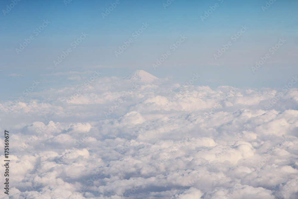 Fototapeta premium Clouds on sky and the Fuji peak above the airspace of Japan photo from airplane window