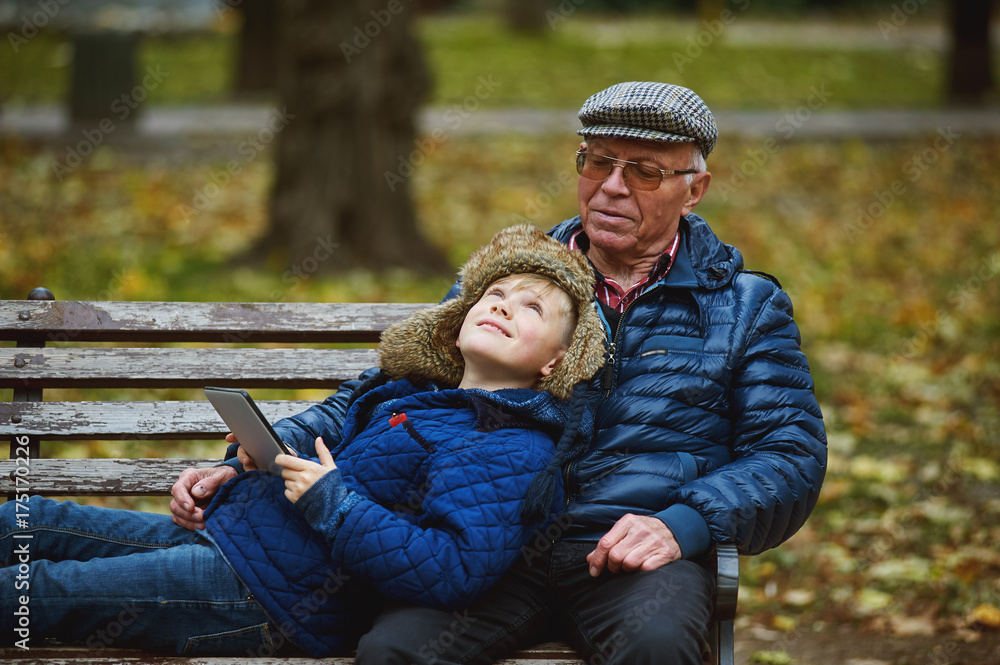 Grandson with grandfather on a walk in the autumn Park . Family values