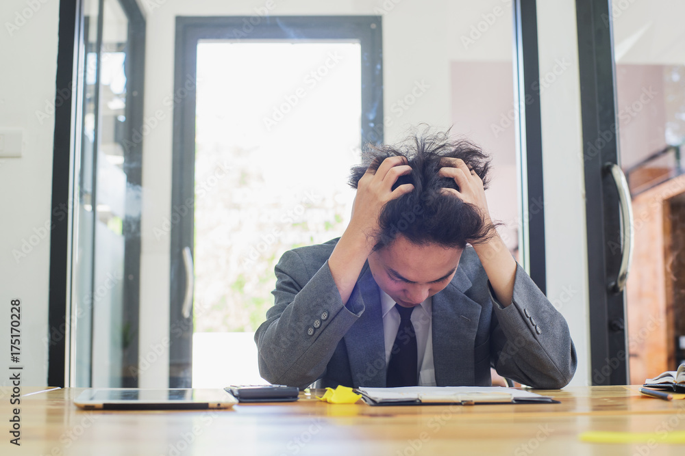 Stressed businessman sitting at workplace and touching his head Stressed businessman sitting at workplace and touching his head