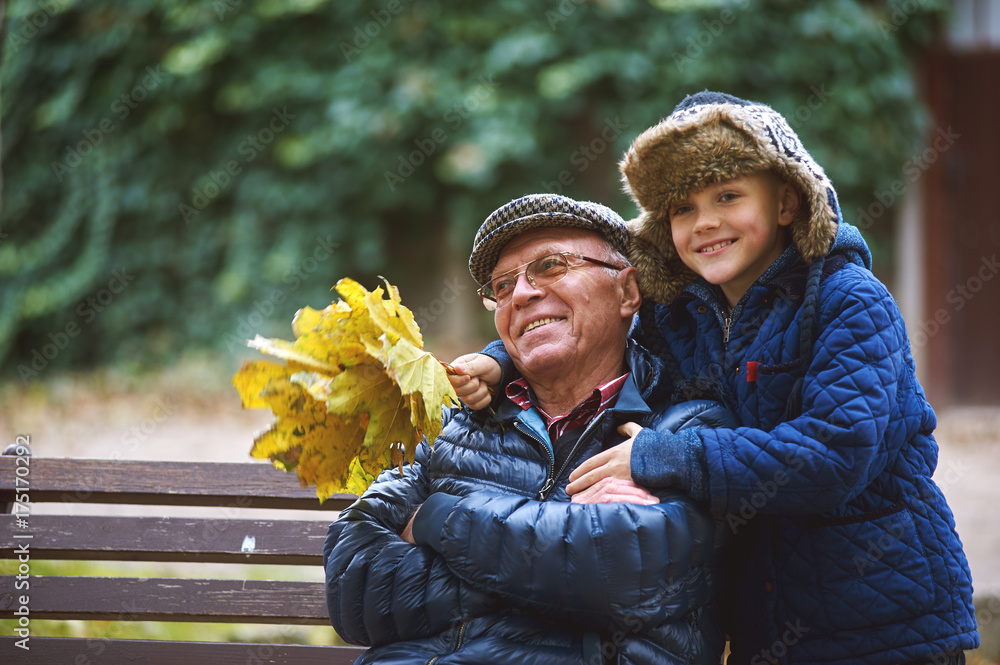 Grandson with grandfather on a walk in the autumn Park . Family values