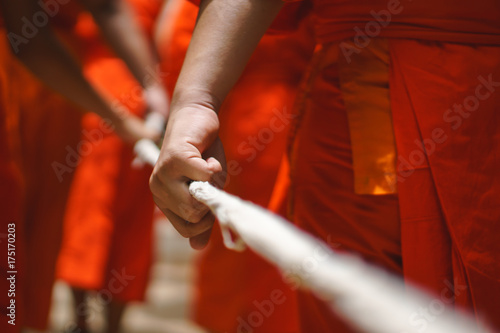 Monk Hand holding big rope for leading people and dead body carrying car to crematory or graveyard as a Buddhism or a sign of dedication of merit