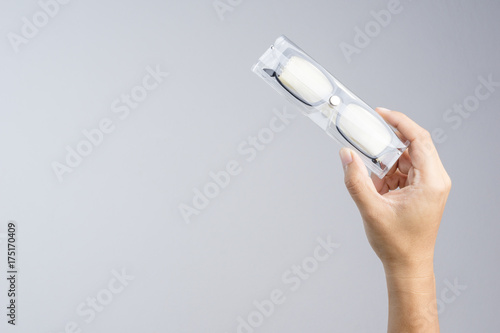 Hand holding plastic case box with clean dust cloth and a pair of black plastic prescription optical glasses