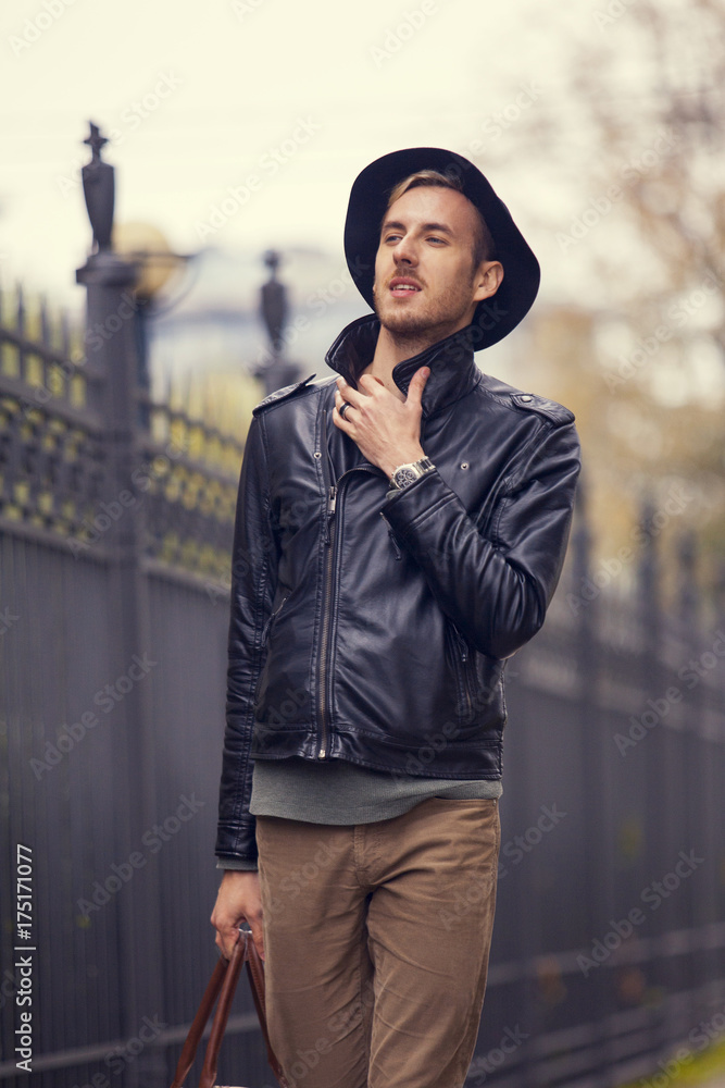 a tourist with a bag in a leather jacket and hat
