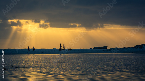 Foto A family walking their dog on the beach at sunset