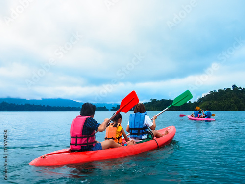 Many family travelers are doing kayaking in natural reservoirs and wearing life jackets for safety.