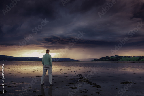 Man Standing on Sea Shore with Dramatic Cloudy background