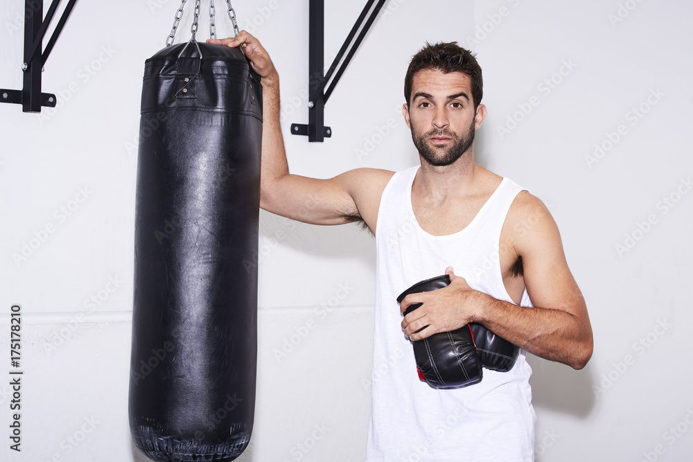 Boxer dude with heavy punch bag in gym, portrait