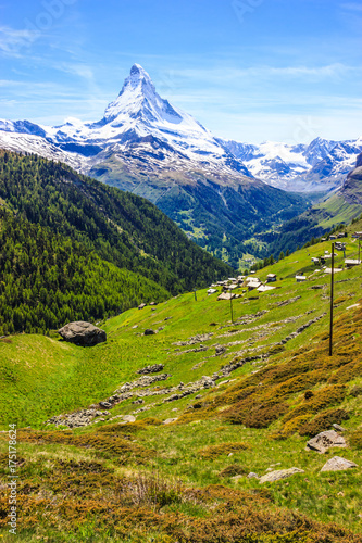 Trail with view of traditional village with the iconic Matterhorn Peak background in summer day, Zermatt, Switzerland, Europe.