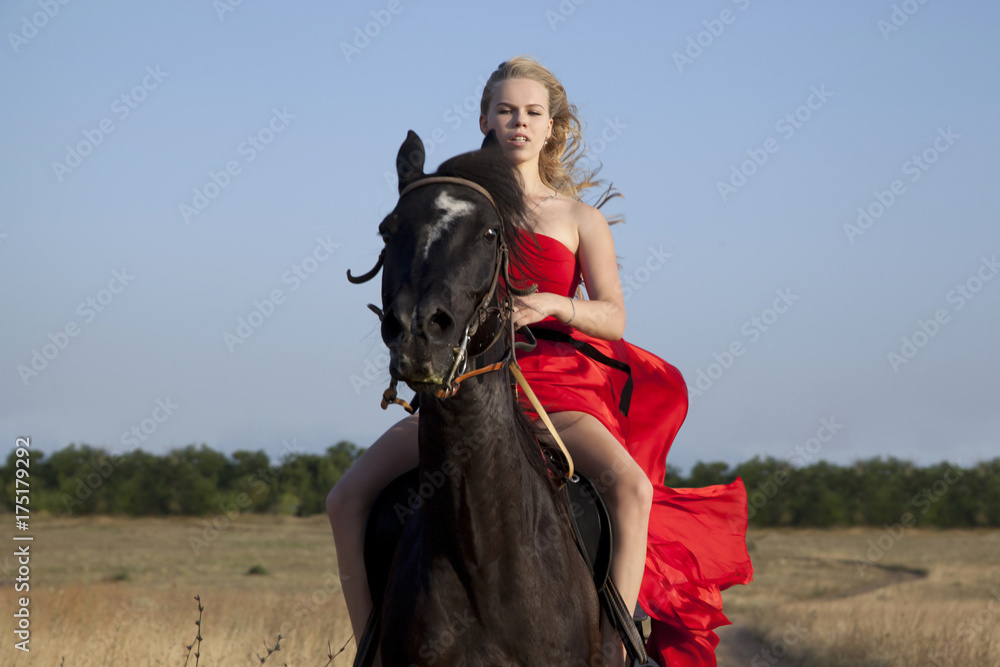 Blonde galloping on stallion. Young woman in red dress fluttering on wind Blonde galloping on stallion. Young woman in red dress fluttering on wind