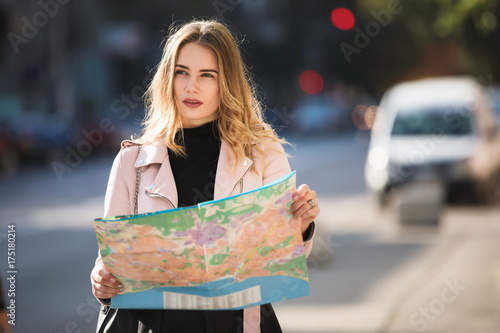 Tourist woman traveller looking to map standing in european city street