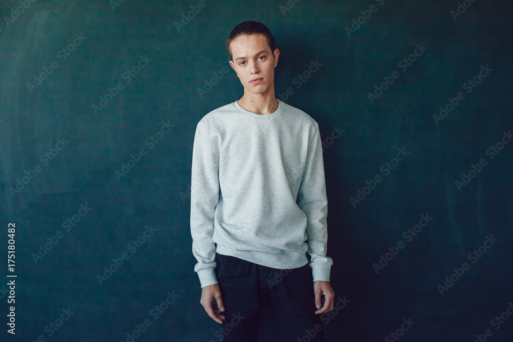 Young man in gray sweatshirt on black background. Mock-up.