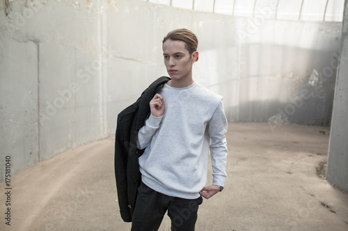 Stylish young man in gray sweatshirt on building background. Mock-up.