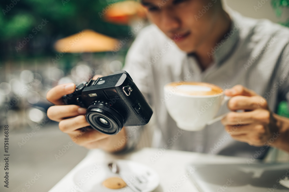 Young man photographer taking picture sitting at table in coffee shop