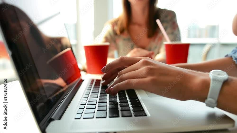 Young Girl Typing On a Laptop Keyboard In Modern Cafe and Drink Coffee