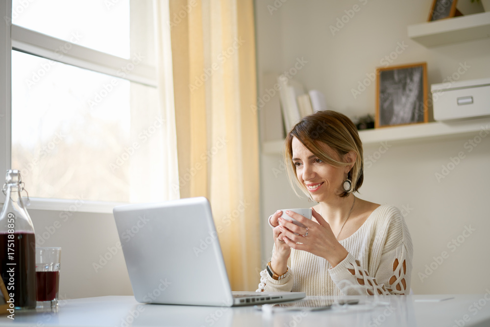 Caucasian woman using laptop for work while sitting in home office/ businesswoman in thirties Caucasian woman using laptop for work while sitting in home office/ businesswoman in thirties