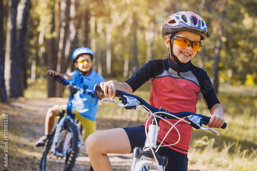 kids on abicycles in the sunny forest. children cycling outdoors in helmet