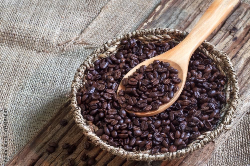 Coffee beans on wooden spoon over basket of coffee beans. Coffee beans on wooden spoon over basket of coffee beans.