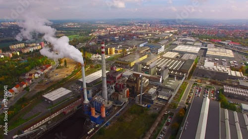 Camera flight over a modern combined heat and power plant. Fuming chimney with sulphur removal unit. Heavy industry from above. Power and fuel generation in European Union. 