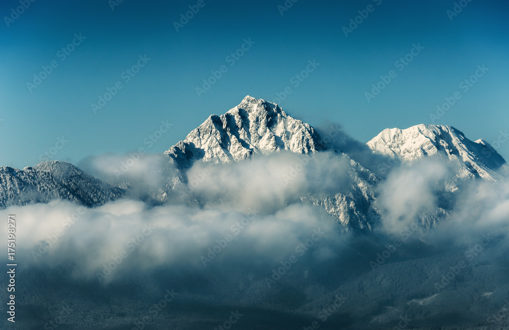 Mountain peak with snow in cloud on blue sky background, travel destination