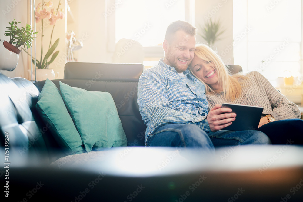 Caucasian couple using tablet while sitting on sofa in living room