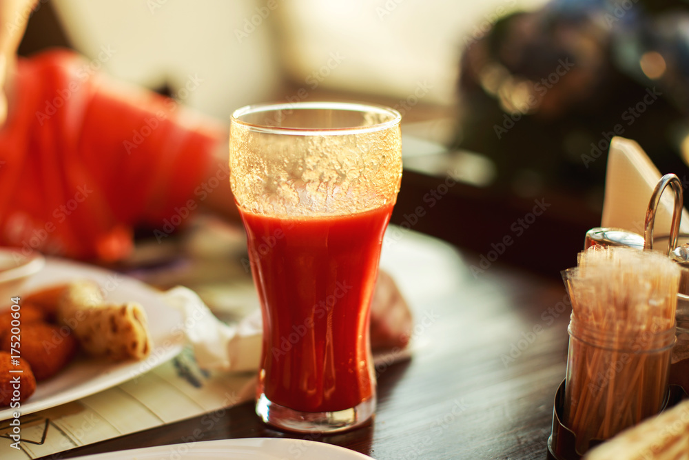 a glass of tomato juice on a table a glass of tomato juice on a table