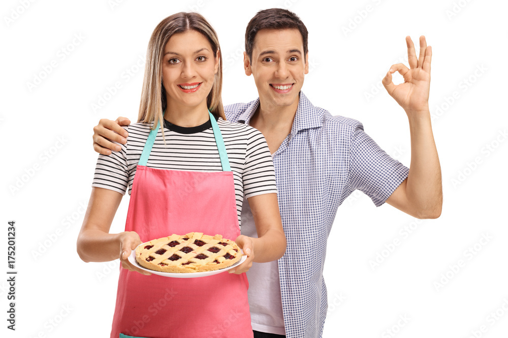 Woman holding a pie and young man making ok sign