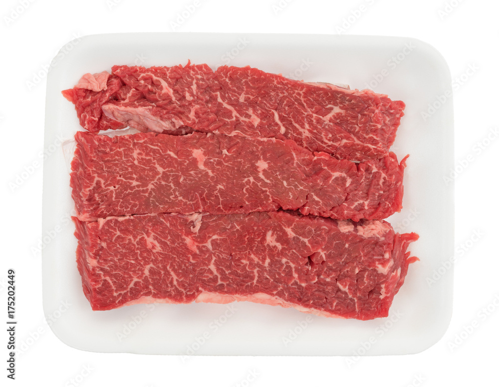 Top view of raw beef loin sirloin grilling tips on a foam butcher tray isolated on a white background.