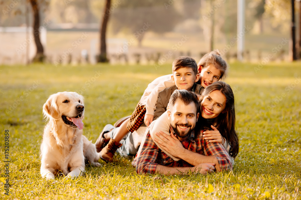family lying in pile on grass family lying in pile on grass