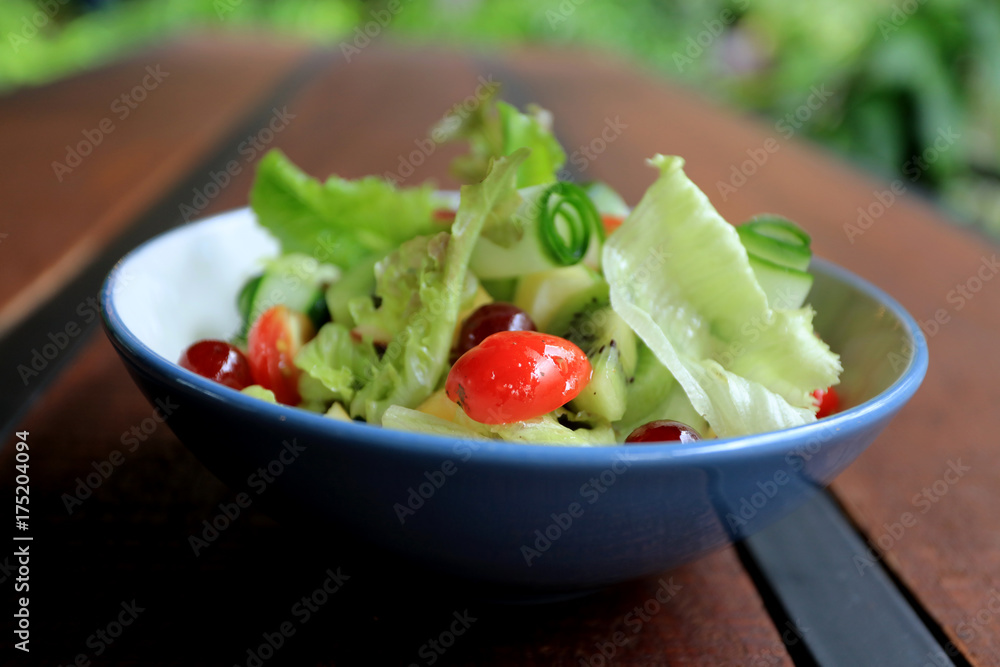 Bowl of healthy fresh fruit salad on wooden table, Delicious salad with mix fruit and vegetable, organic salad for healthy Bowl of healthy fresh fruit salad on wooden table, Delicious salad with mix fruit and vegetable, organic salad for healthy