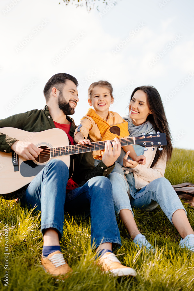 man playing guitar with family