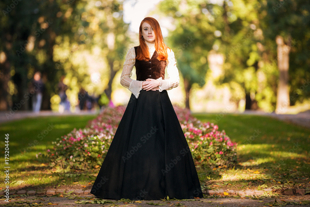 Red-haired woman in Victorian outfit with autumn park Red-haired woman in Victorian outfit with autumn park