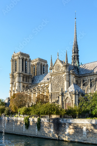Three quarter view of the southern side of Notre-Dame de Paris cathedral by a sunny evening at the beginning of fall with the river Seine in the foreground. © olrat