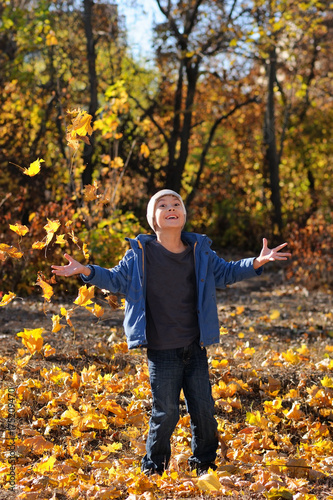 Happy child throws up leaves in autumn park © Anatoliy Sadovskiy