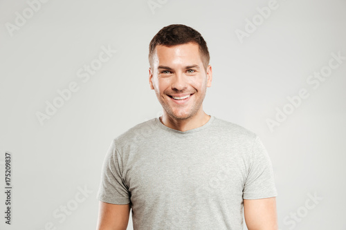 Happy young man dressed in grey t-shirt isolated