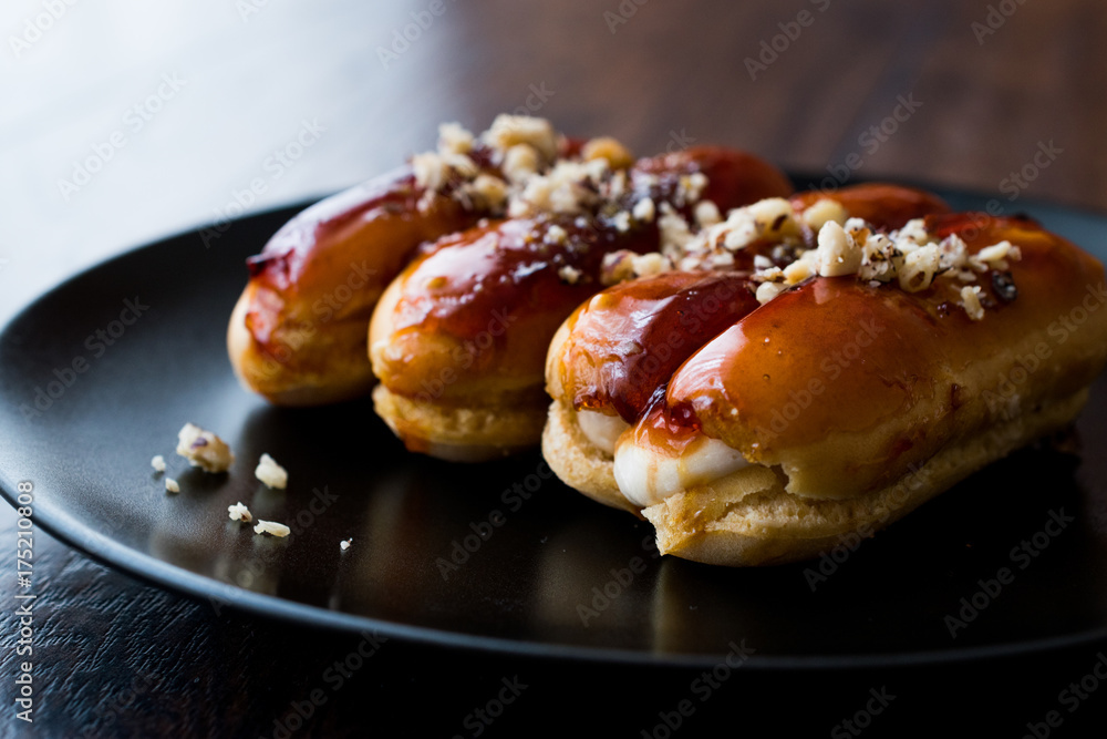 Caramel Eclairs with Hazelnut and cream in black plate.