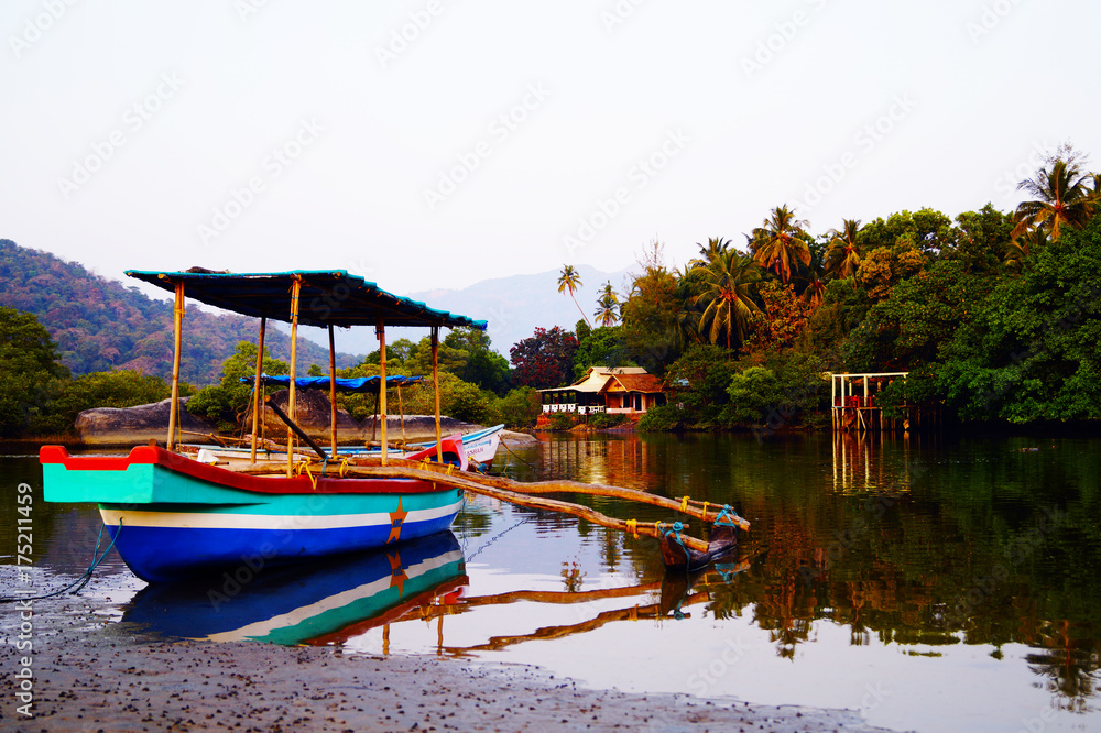 Traditional indian boat near Paloem beach. Small lagoon on the sunset. Excursion boat on the shore.