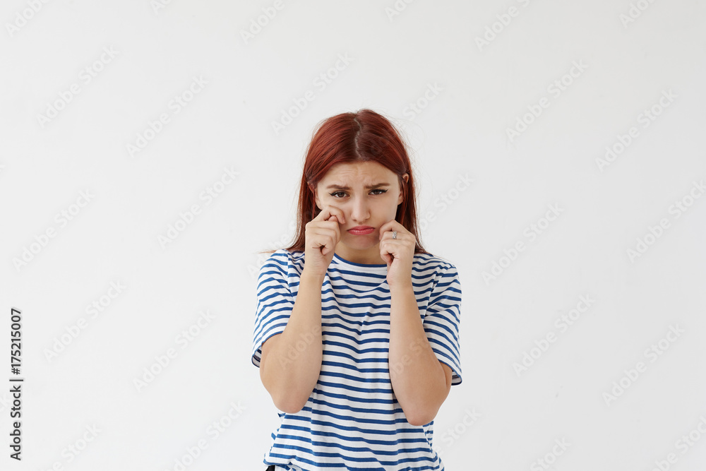 Portrait of mournful sad female student pouting and crying, wiping tears from her pretty face, feeling upset and unhappy about stress and failures at college or personal problems with her boyfriend Portrait of mournful sad female student pouting and crying, wiping tears from her pretty face, feeling upset and unhappy about stress and failures at college or personal problems with her boyfriend