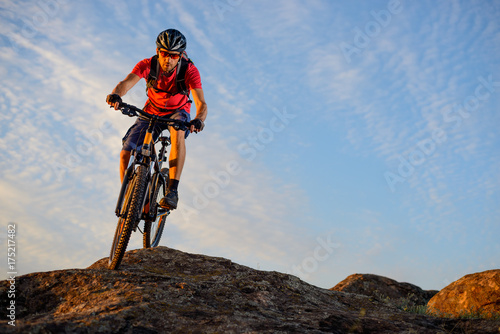 Cyclist in Red Riding the Bike Down the Rock on the Blue Sky Background. Extreme Sport and Enduro Biking Concept.