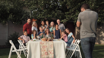 Cheerful family standing at table in garden and posing for photo.