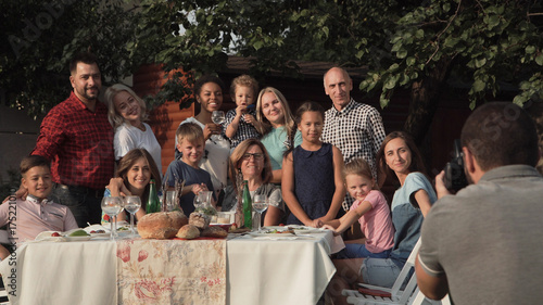 Cheerful family standing at table in garden and posing for photo.