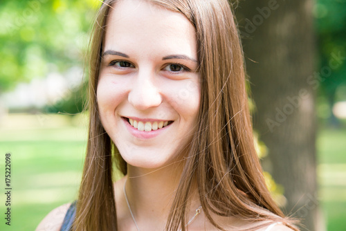 Portrait young smiling woman with long hair in summer park