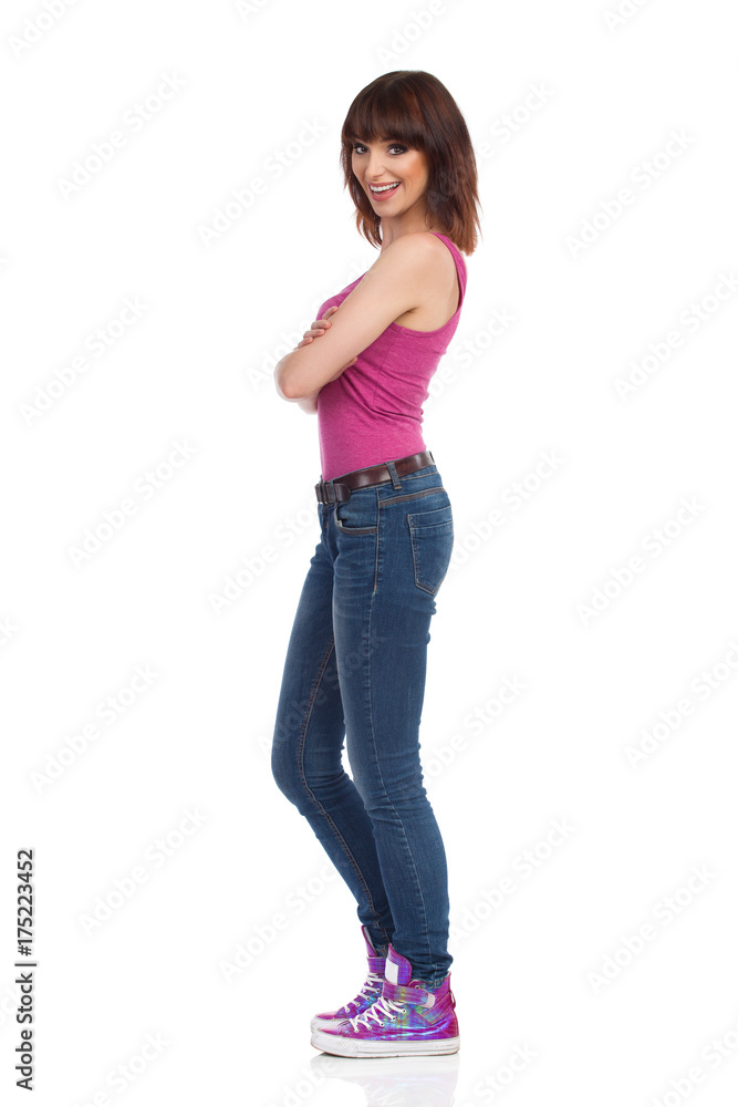 Smiling Woman Is Standing With Arms Crossed And Looking At Camera. Side View Smiling Woman Is Standing With Arms Crossed And Looking At Camera. Side View