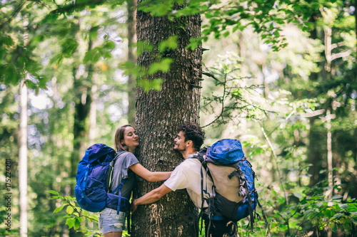 Hiking couple. Young couple with backpacks hugging tree and having fun  © Astarot