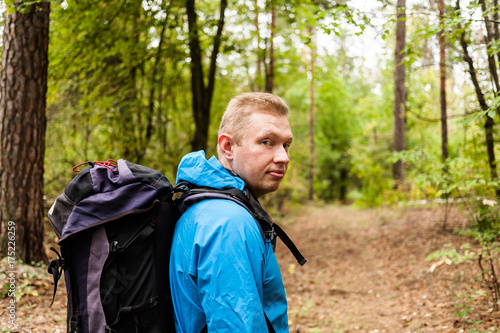 Hiker with backpack is walking in the autumn forest.